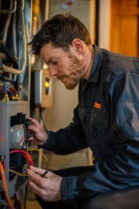 Home 23 Homeowner checking a thermostat and inspecting a furnace during a troubleshooting check